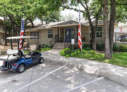 A golf cart is parked in front of a building with an American flag on it.