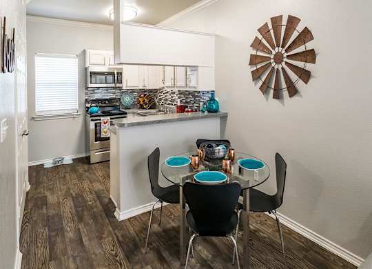 A kitchen with a table and chairs in front of it.