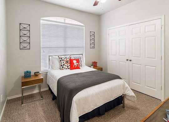 A bedroom with a bed, a nightstand, and a ceiling fan.