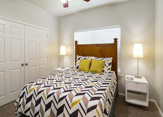A bedroom with a bed, nightstand, and a ceiling fan.