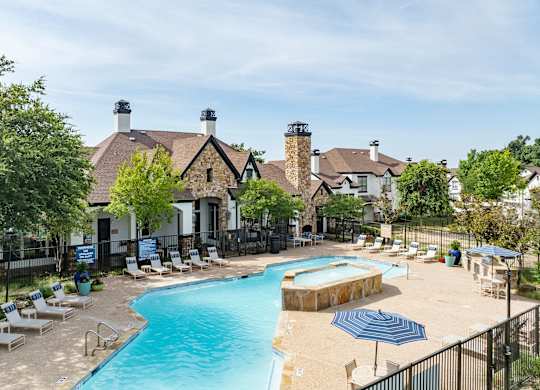 Aerial view of resort-style pool with sundeck and stone clubhouse at Villas of Vista Ridge.