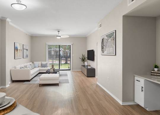 Bright living room with wood-style flooring, crown molding, and sliding glass door to patio.