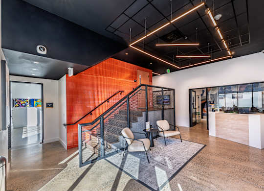 A modern office lobby with a staircase and a glass railing.