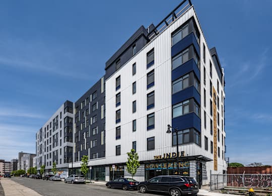A modern multi-story building with a black car parked in front.