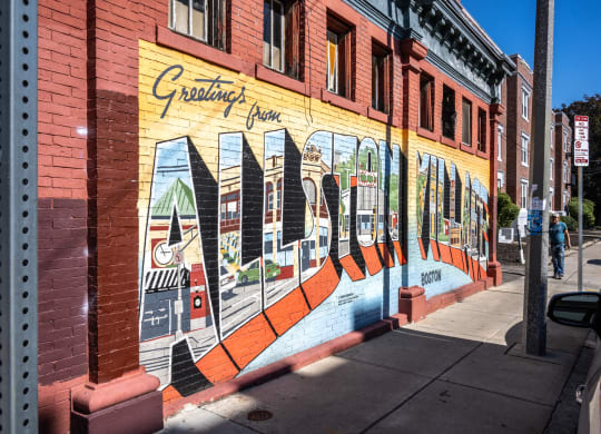 A mural on the side of a building that reads Allston Village, Allston MA