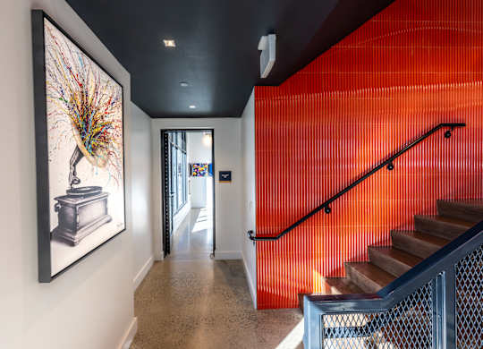 A hallway with a staircase and a painting of a peacock on the wall.