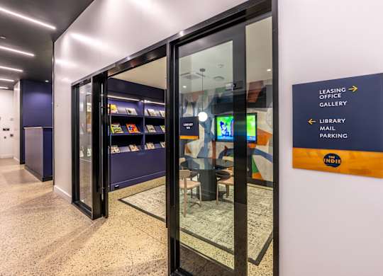 A sign in a hallway points to the leasing office, library, and parking.