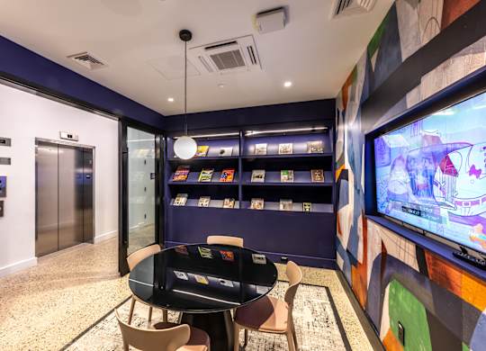 A room with a television, chairs, and a table.