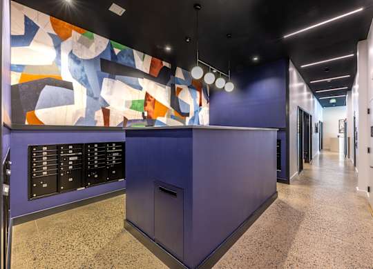 A hallway with a purple reception desk and a colorful mural on the wall.