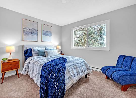 A bedroom with a bed, a chair, and two pictures on the wall.