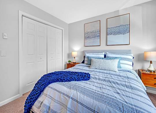 A bedroom with a bed covered in a blue and white striped comforter.