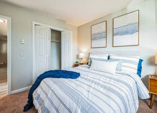 A bedroom with a large bed and two framed pictures on the wall.