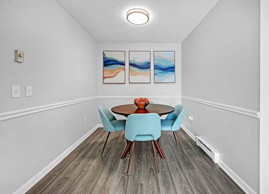 A dining room with a round table and blue chairs.
