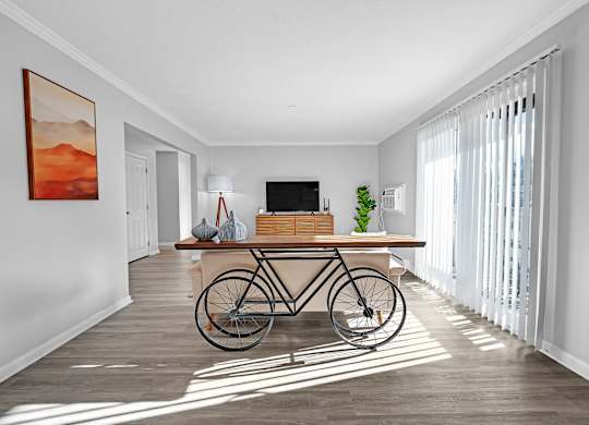 A room with a bicycle leaning against the wall and a painting hanging above it.