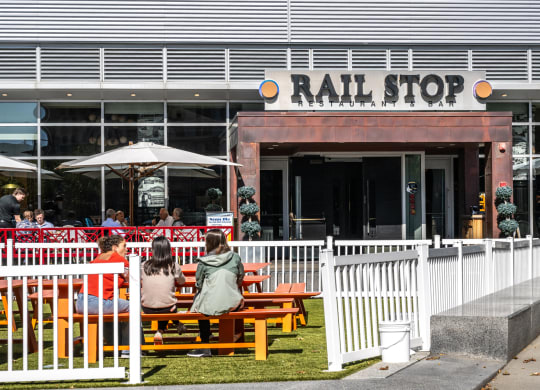 People sitting on benches outside at Railstop Restaurant, Boston Landing, Allston MA