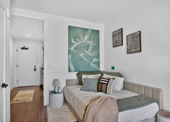 A bedroom with a bed, nightstand, and two wall art pieces at The Indie in Allston.