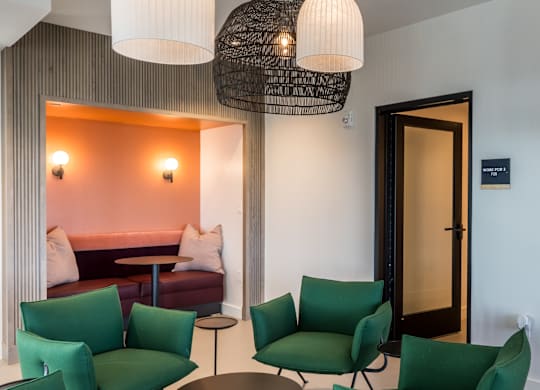 A room with green chairs and a round table.