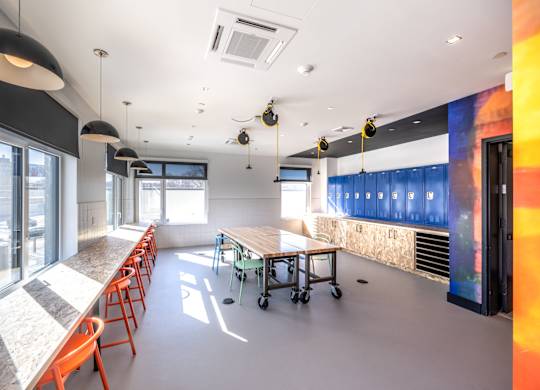 A room with a long table and chairs on the left side and a wall with a colorful mural on the right side.