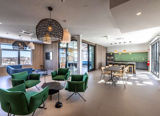 A modern room with green chairs and a large window overlooking a cityscape.