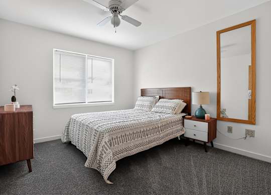 A bedroom with a bed, nightstand, and a ceiling fan.