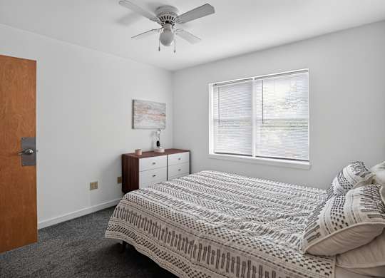 A bedroom with a bed, dresser, and window.