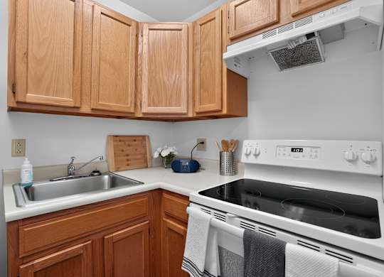 A kitchen with wooden cabinets and a white stove top oven.