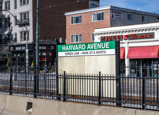 a sign in front of a metal fence identifying the Harvard Avenue MBTA Green Line stop, Allston MA