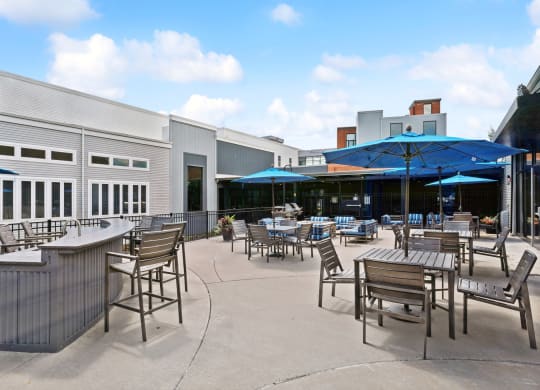 a patio with tables and chairs and umbrellas in front of a building at The Tannery, Glastonbury, Connecticut