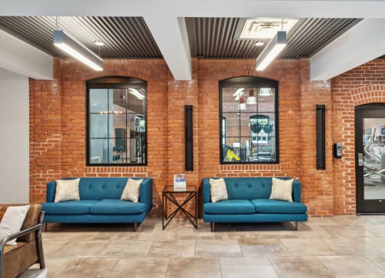 a lobby with two blue couches in front of a brick wall at The Tannery, Connecticut, 06033