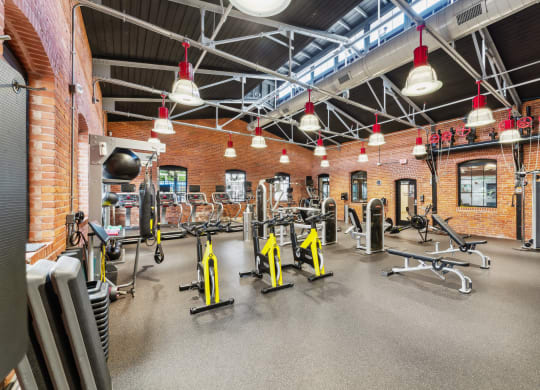 a gym with weights and cardio equipment and brick walls at The Tannery, Connecticut