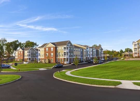 A road with a car on it and apartment buildings on both sides.