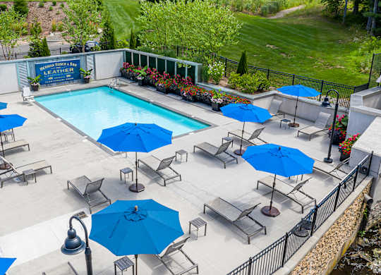 A pool surrounded by blue umbrellas and chairs.