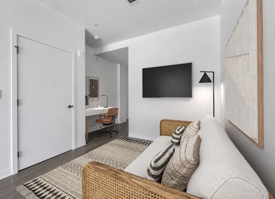 A modern living room with a couch, a chair, a desk, and a television.