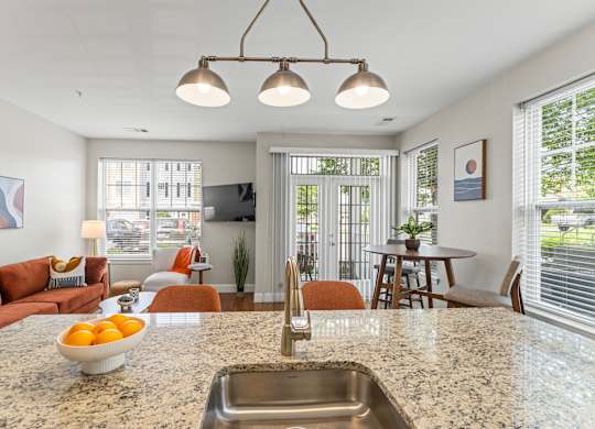 A kitchen with a marble countertop and a bowl of oranges on it.