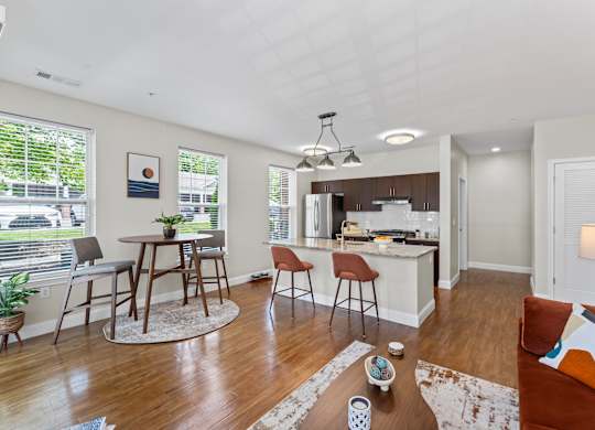 A well-lit, modern kitchen and living room with wooden floors and furniture.