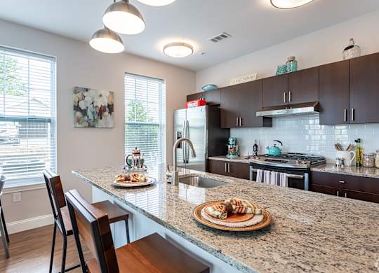 A kitchen with a table and chairs with food on it.