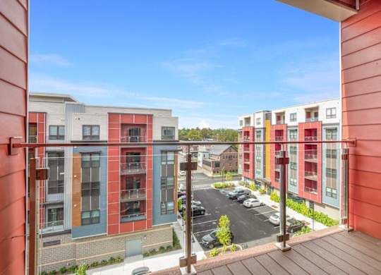 A view from a balcony of a parking lot and apartment buildings.