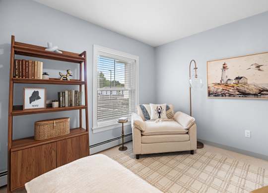 A living room with a couch, a bookshelf, and a painting on the wall.