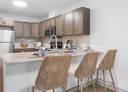 A kitchen with a white countertop and brown chairs.