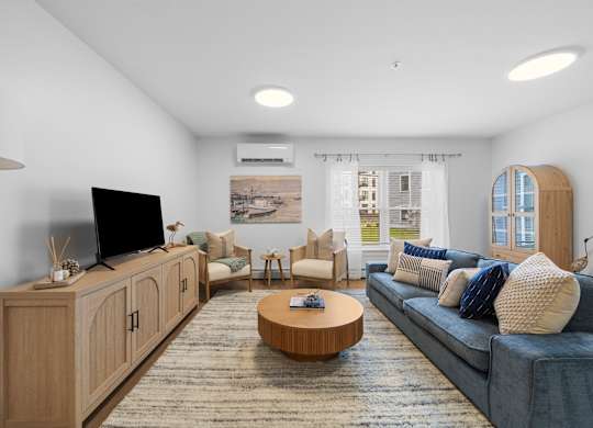 A living room with a blue couch, a wooden cabinet, and a flat screen TV.