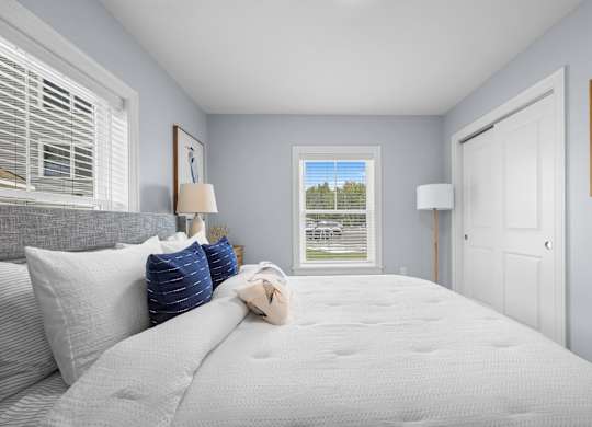 A bedroom with a large bed and a window overlooking a grassy area.