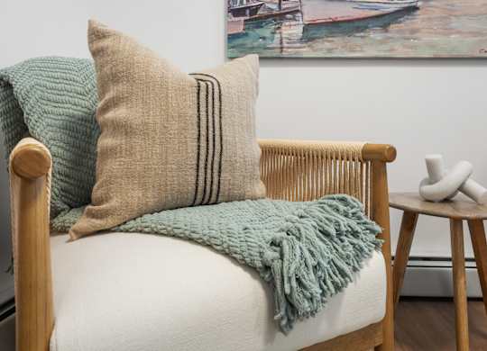 A chair with a white cushion and a green throw blanket on it.