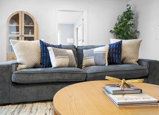 A grey couch with blue and white pillows sits in a living room.