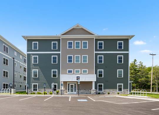 A large grey building with a parking lot in front.