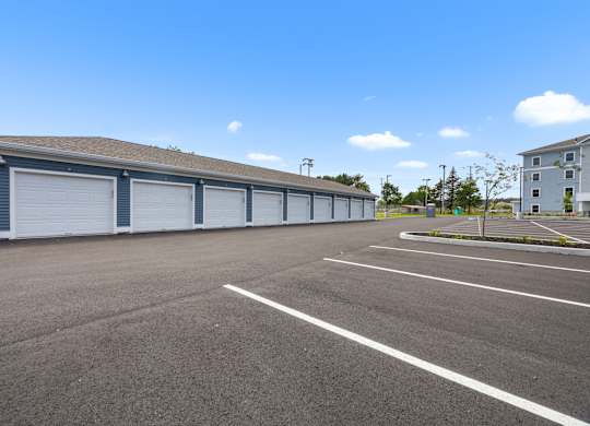 A large, empty parking lot with garage bays in the background.
