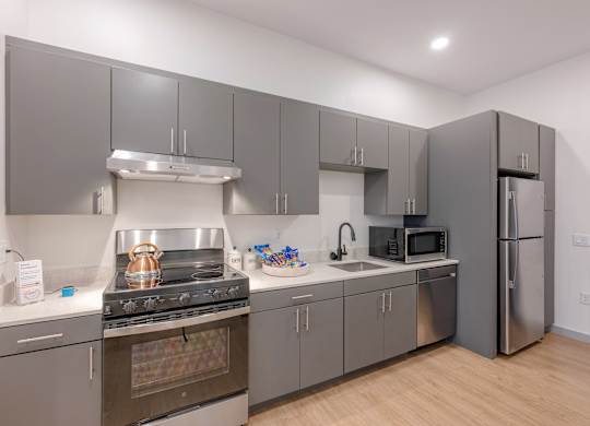 A modern kitchen with stainless steel appliances and grey cabinets at Seacoast Residences Apartments, Oakland, ME