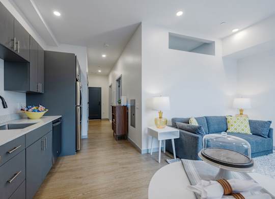 A modern kitchen with a blue couch in the living room at Seacoast Residences Apartments, Oakland, Maine
