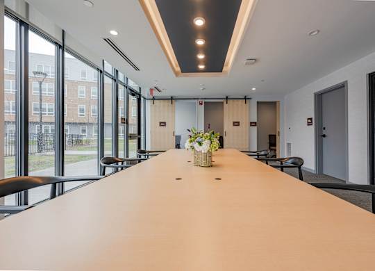 A long conference table with chairs and a vase of flowers on top at Seacoast Residences Apartments, Maine