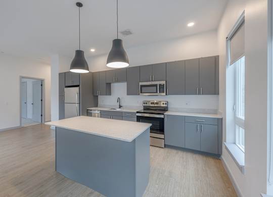 A modern kitchen with a central island and pendant lights at Seacoast Residences Apartments, Oakland, ME