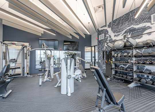 A gym with a variety of equipment including weights and machines at Seacoast Residences Apartments, Oakland